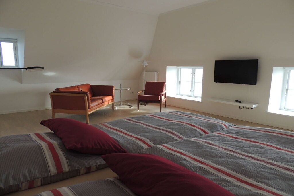 A bedroom with a large bed, a sofa, a chair, and a TV.