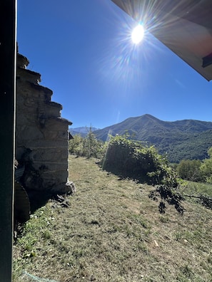 A stone building with a clear view of a mountainous landscape under a bright sun. - An exceptional sheep farm on the hills above Ercé — the wild and unspoiled Ariège (Ercé)
