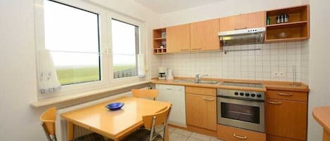 A compact kitchen with a dining area, a window, and a view of the outdoors.