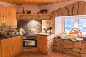 A kitchen with wooden cabinets, a stone backsplash, and a built-in oven. - 5 in the house Traumweide (Oberwiesenthal)