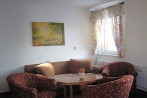 A living room with a sofa, two armchairs, a small table, and a painting on the wall. - 5 in the house Traumweide (Oberwiesenthal)