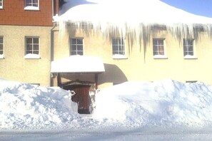 A building with a snow-covered entrance and icicles hanging from the roof. - 5 in the house Traumweide (Oberwiesenthal)