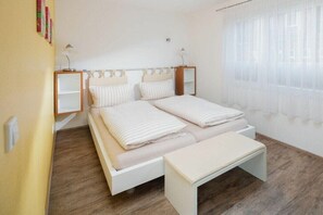 A bedroom with a bed, bedside tables, and a window with curtains. - Holiday apartment in Juist with swimming pool (Juist)