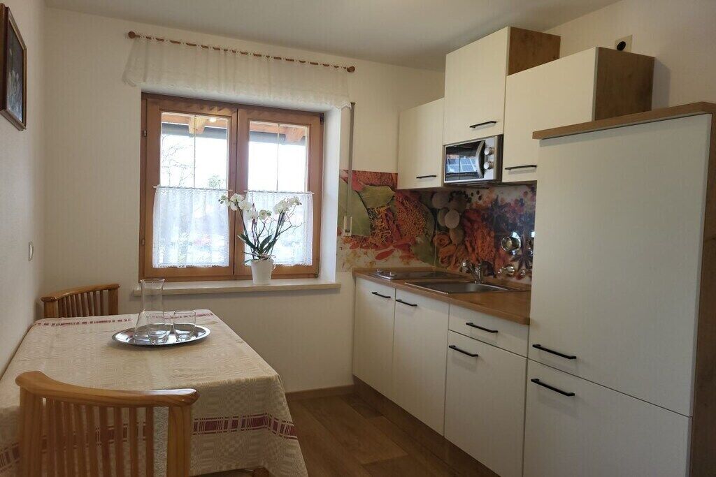 Une cuisine compacte avec des meubles blancs, un four à micro-ondes et une fenêtre donnant sur un beau paysage.