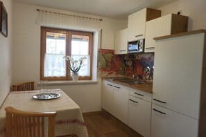 A compact kitchen with white cabinets, a microwave, and a window with a view. - Holiday apartment with 2 bedrooms (Bernau a. Chiemsee)