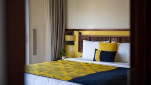 Una habitación de hotel con una cama, cortinas, una lámpara y un teléfono instalado en la pared.