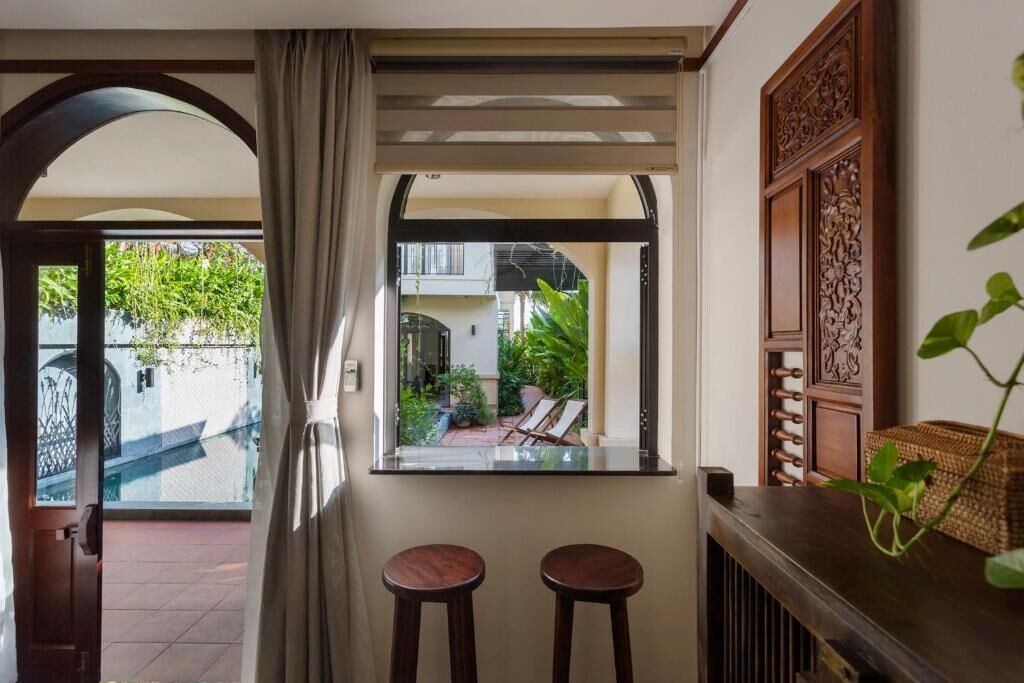 A room with a view of a courtyard, a window with a view, and a bar area with stools.
