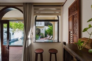 A room with a view of a courtyard, a window with a view, and a bar area with stools. - La Maison Gao (Hoi An Dong ward)
