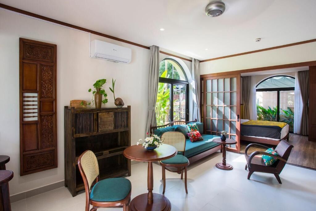 Um quarto com sofá, cadeiras, uma mesinha e estante.