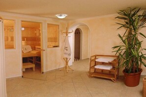 A room with a wooden bench, a plant, and a towel rack. - Haus Daheim/Brennerspitz (Neustift)