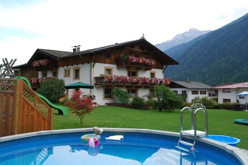 Eine traditionelle Chalet mit Schwimmbad, umgeben von üppiger Vegetation und Bergen.