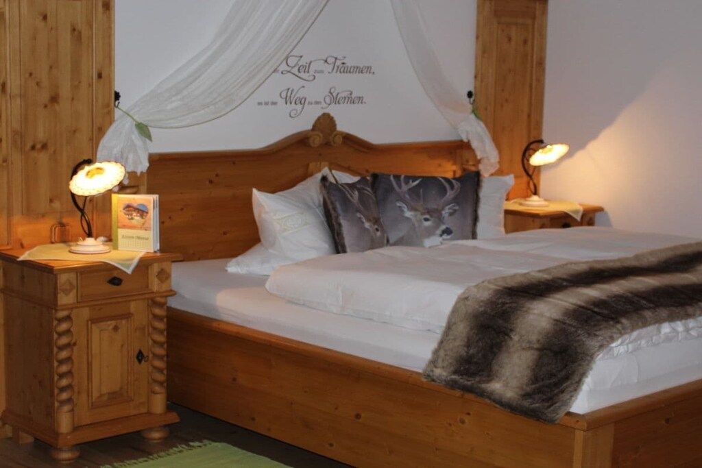 Una cama de madera con dosel, dos lámparas de noche y una pared con una frase decorativa.