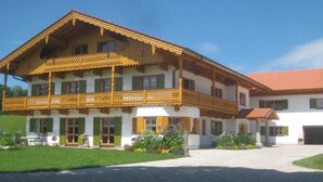 Ein zweistöckiges Gebäude mit Balkon, überdachter Veranda und rotem Ziegeldach.