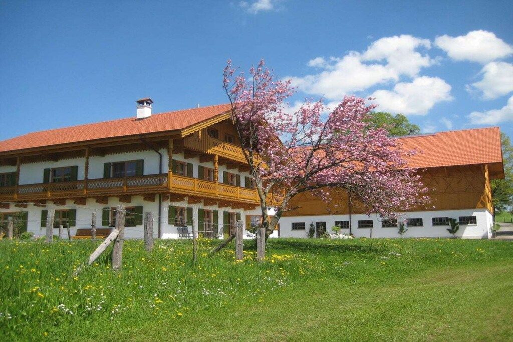 A two-story building with a red-tiled roof and a balcony.