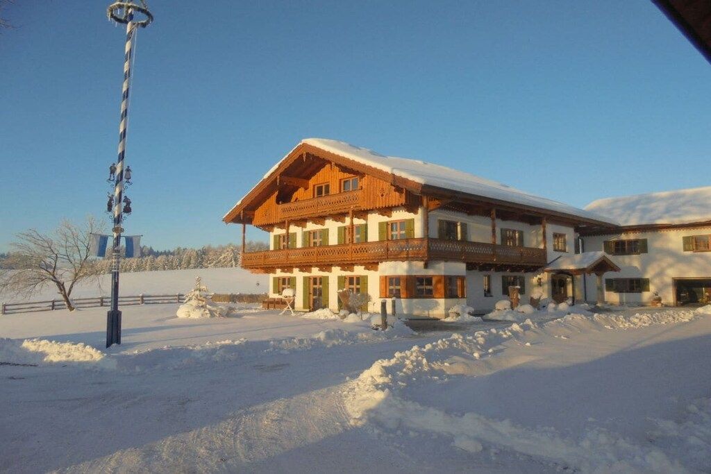 A two-story building with a balcony, surrounded by snow.