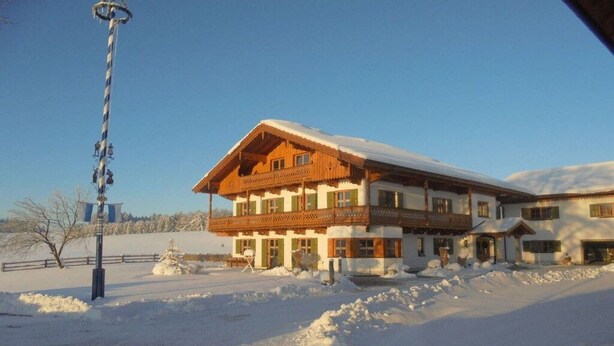 Ein zweistöckiges Gebäude mit Balkon, umgeben von Schnee.