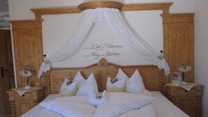 Ein Schlafzimmer mit einem Himmelbett, weißer Bettwäsche und einem Baldachin.