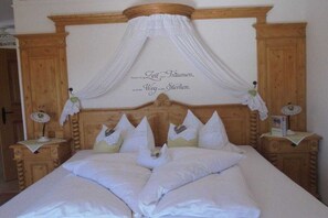 Ein Schlafzimmer mit einem Himmelbett, weißer Bettwäsche und einem Baldachin.