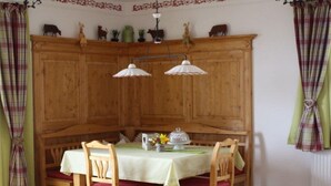 Ein Essbereich mit einem Holzkabinett, zwei Pendelleuchten und einem für vier Personen gedeckten Tisch mit Stühlen.