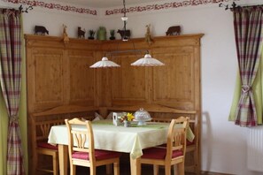 Ein Essbereich mit einem Holzkabinett, zwei Pendelleuchten und einem für vier Personen gedeckten Tisch mit Stühlen.