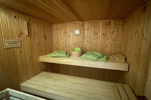 A sauna room with wooden walls, a bench, and towels.