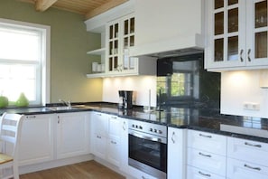 A kitchen with white cabinetry, a black countertop, and a built-in oven.