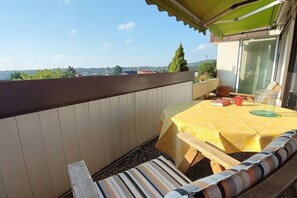 Ein Balkon mit Tisch und Stühlen und Blick auf die Stadt, dazu ein grünes Markisen