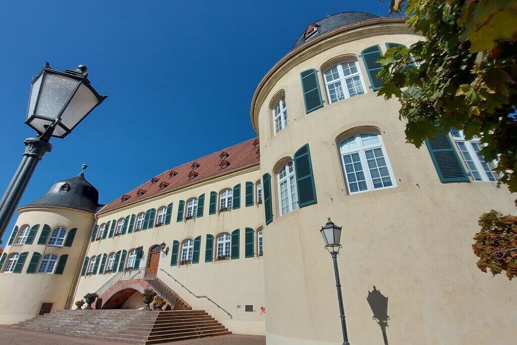 A building with a curved facade, multiple windows with shutters, and a staircase leading to an entrance.