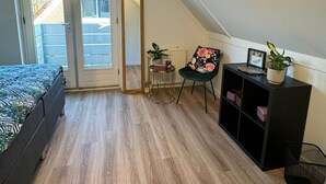Ein Schlafzimmer mit einem Bett, einem Sessel, einem kleinen Tisch und einer Heizung.