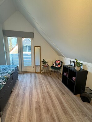 Een slaapkamer met een bed, een stoel, een klein tafeltje en een radiator.