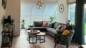 Ein modernes Wohnzimmer mit einer Eckcouch, einem runden Couchtisch und einem gemusterten Sessel.
