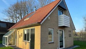 Ein eingeschossiges Haus mit rotem Ziegeldach, einer Veranda und einer kleinen angebauten Garage.