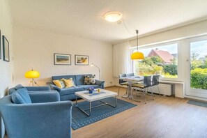 Ein modernes Wohnzimmer mit einer Sofagarnitur, einem Couchtisch und einem Essbereich mit Stühlen und einem Tisch.