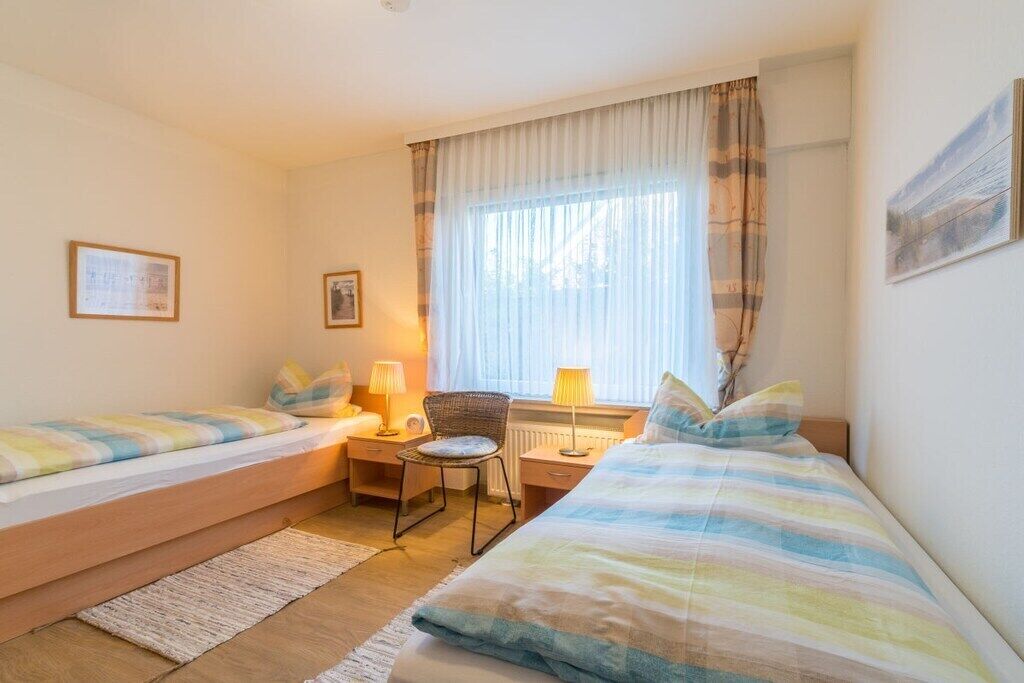 Ein Hotelzimmer mit zwei Betten, einem Schreibtisch, einem Stuhl und einem Fenster mit Vorhängen.