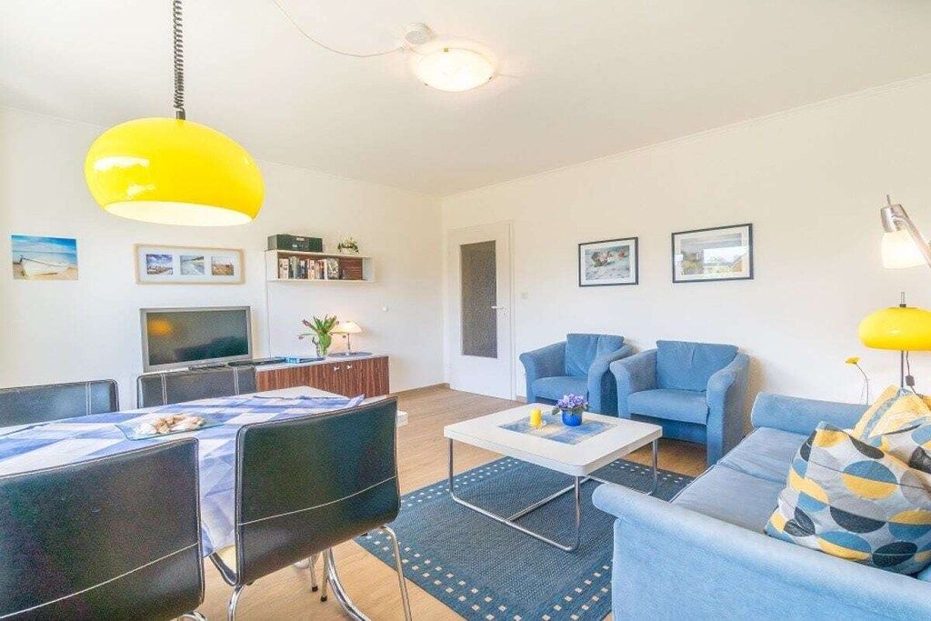 Un salon moderne comprenant un canapé, des fauteuils, une table basse et un téléviseur.