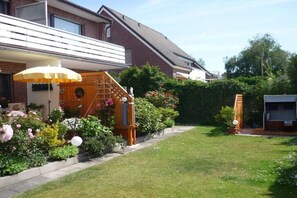 Ein Wohnhaus mit gepflegtem Garten, einer Holztreppe und einem deutlichen Weg zum Eingang.