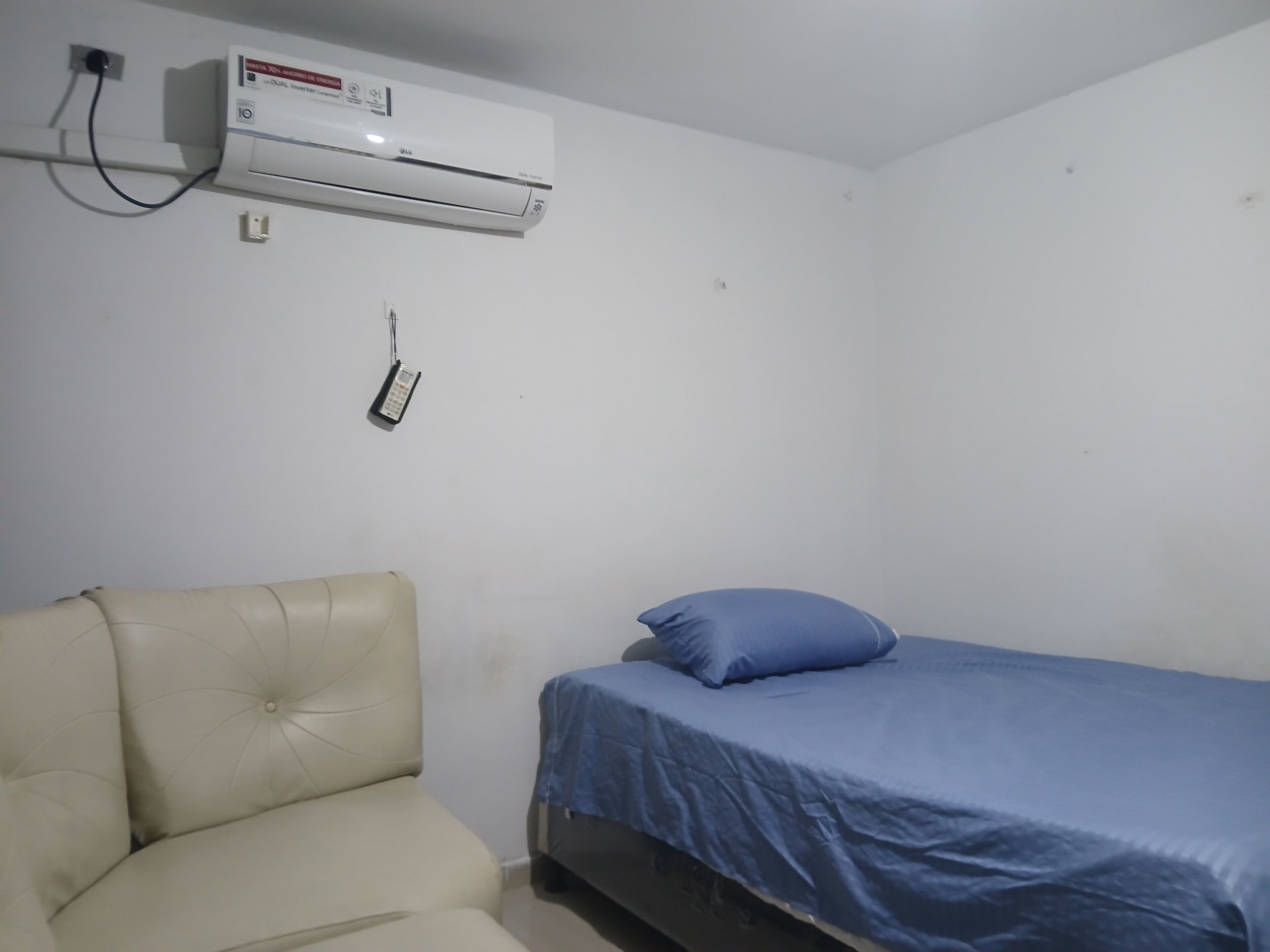 Une chambre avec un lit, une chaise et un appareil de climatisation.