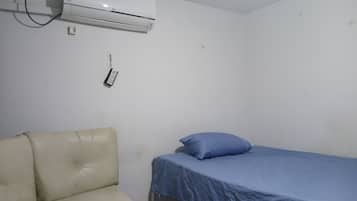 Une chambre avec un lit, une chaise et un appareil de climatisation.