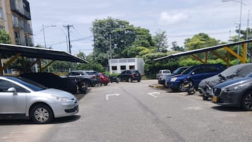 A parking lot with multiple cars and motorcycles, a building in the background, and a clear sky.