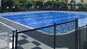 A swimming pool with a checkered deck, surrounded by palm trees and residential buildings. - 3-Bedroom Family Apartment with Pool in Yopal (Villavicencio)