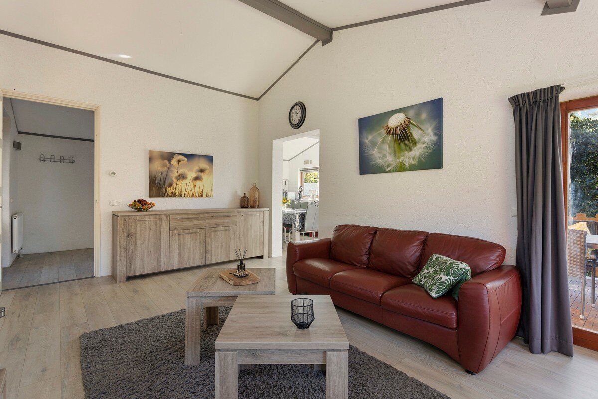 Een moderne woonkamer met een leren bank, een salontafel en kunstwerken aan de muren.