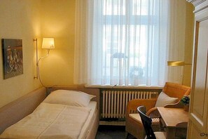 A hotel room with two beds, a chair, a table, a lamp, and a window with curtains. - in Villa Fortuna by the sea - Apartment 1 (Bansin)
