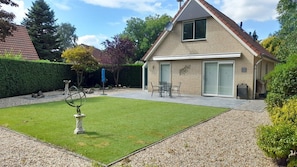 Een huis met een verzorgd gazon, een terras met tuinmeubilair en een schotelantenne.