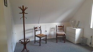 A room with two wooden chairs, a coat rack, a white dresser, and a radiator. - Wighenerhorst Bungalow Park - 39 (Wijchen)