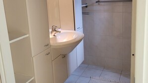 A bathroom with a white sink, a mirror, and a shower area. - Wighenerhorst Bungalow Park - 49 (Wijchen)
