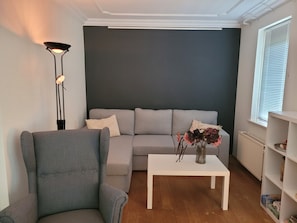 A living room with a grey sofa, a white coffee table, and a floor lamp.