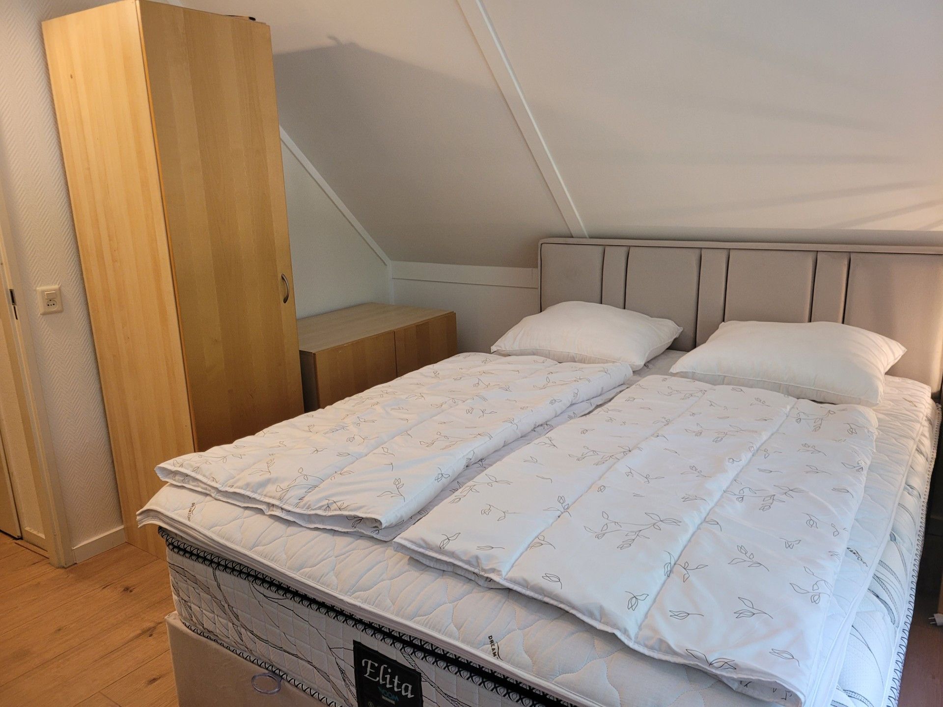 Un dormitorio con cama, mesita de noche y armario de madera.