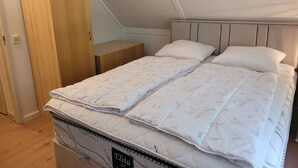 A bedroom with a bed, a nightstand, and a wooden wardrobe. - Wighenerhorst Bungalow Park - 49 (Wijchen)