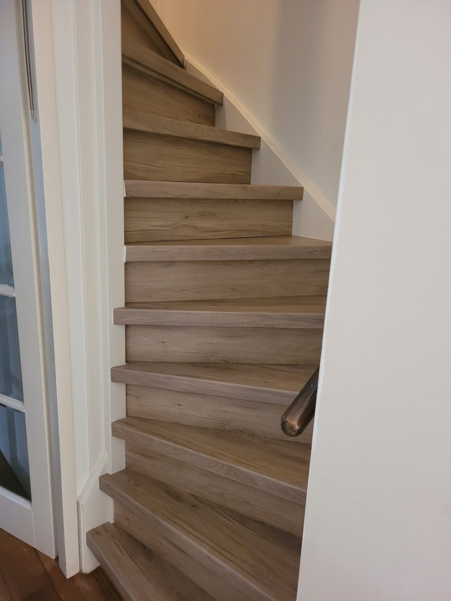 A wooden staircase with a handrail, leading to an upper floor.