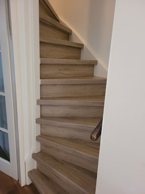 A wooden staircase with a handrail, leading to an upper floor.